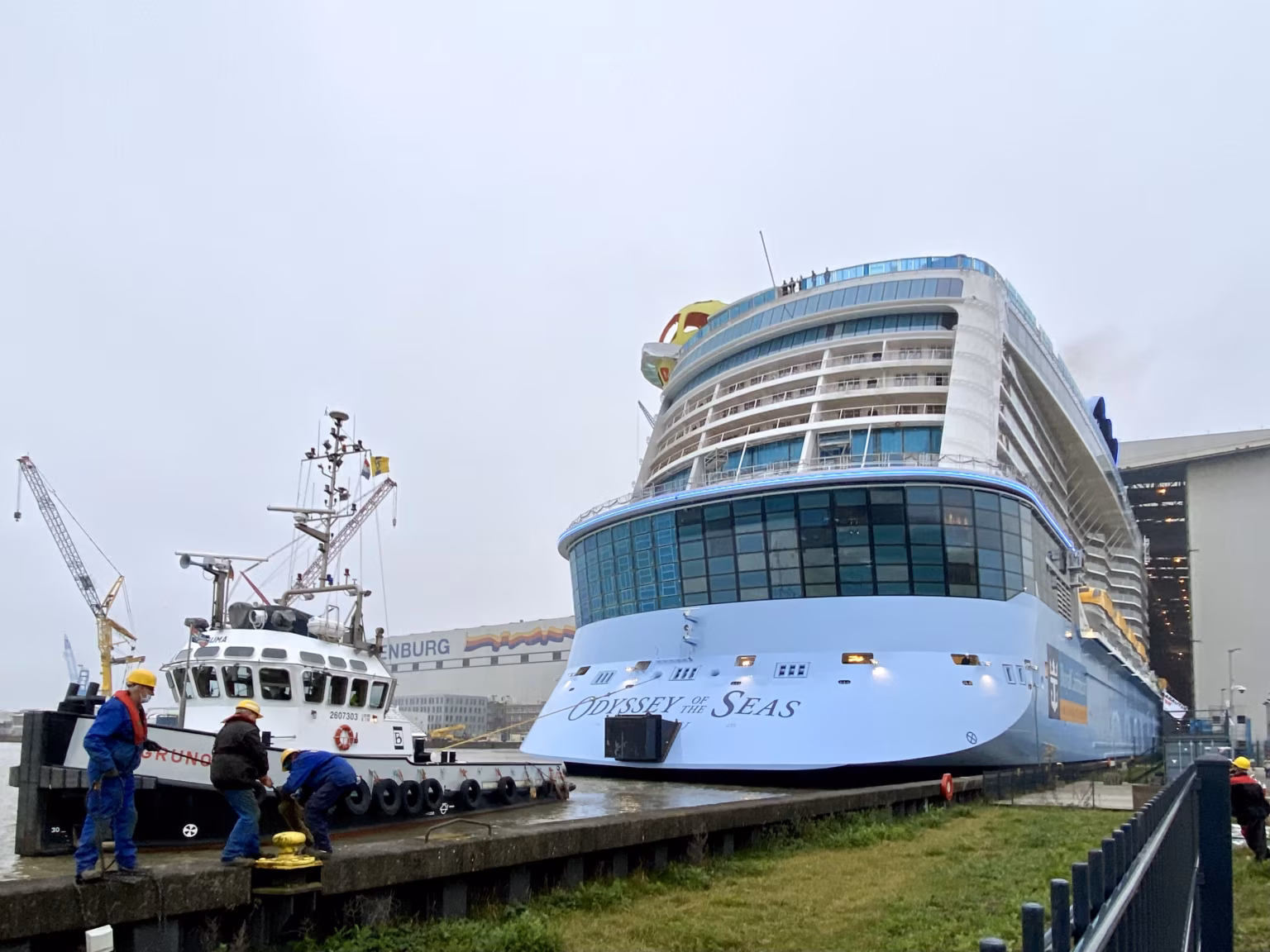 Die Odyssey of the Seas an der Pier, davor ein Schlepper und Werftarbeiter